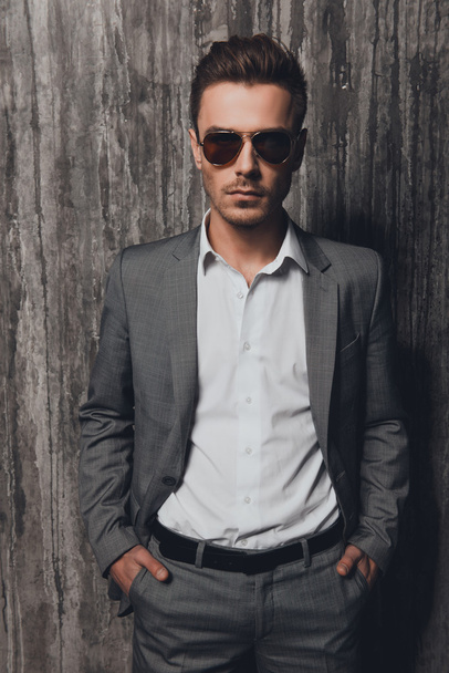 Stylish man holding hands in pockets on the grey background - Fotografie, Obrázek