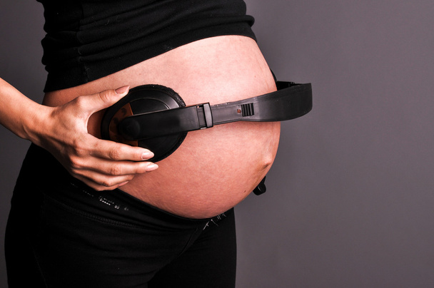 vientre de mujeres embarazadas y auriculares, aislado en negro
 - Foto, Imagen