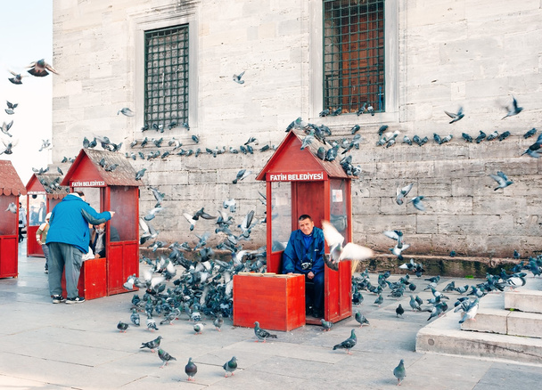 ISTANBUL , TURKEY. View Yeni Cami New Mosque. Man feeding pigeons. - Фото, зображення