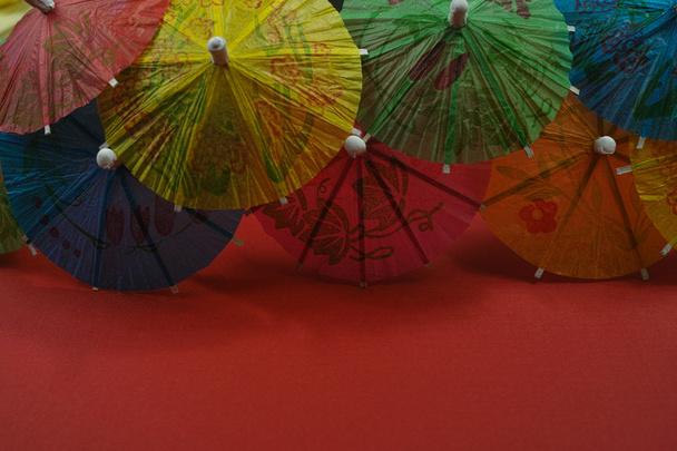 Colorful paper umbrellas, copy space, on red background - 写真・画像