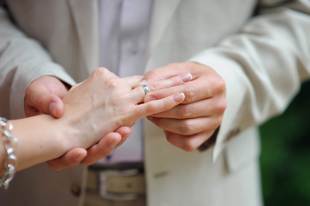 Hands with rings Groom putting golden ring on brides finger - 写真・画像