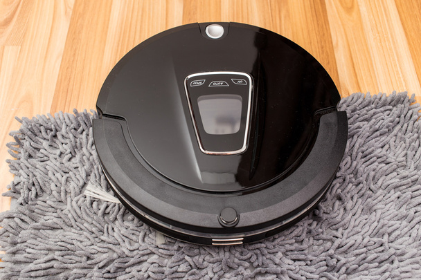 Robotic vacuum cleaner on wood parquet floor - Foto, afbeelding