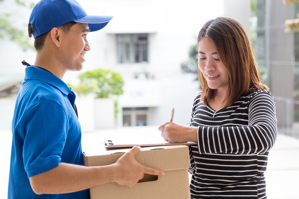 Asian woman signing receipt of delivered package - Photo, image
