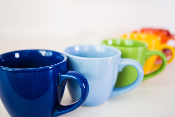 стопка барвистих чашок кави на білому дерев'яному фоні
 - Фото, зображення