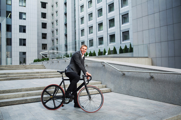 businessman with the bike going up the stairs on the background of business centers - Foto, imagen