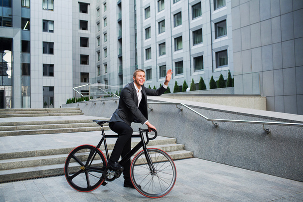 businessman with the bike going up the stairs on the background of business centers - Zdjęcie, obraz