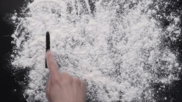 A hand writing on white flour - Footage, Video