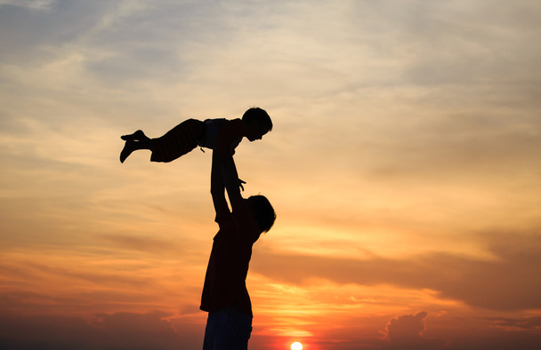 father and son silhouettes play at sunset - Фото, изображение