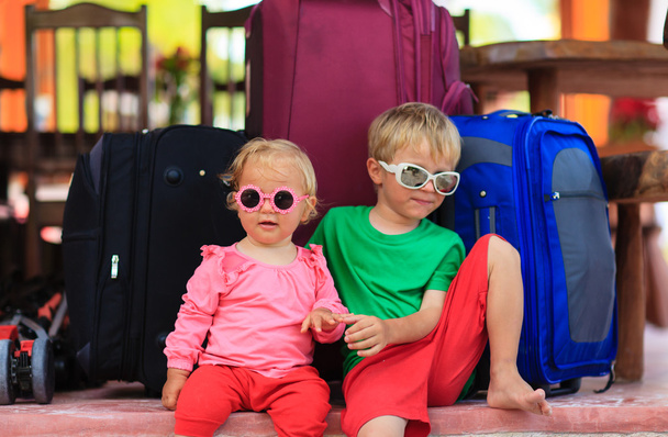 旅行の準備にスーツケースの上に座って小さな男の子と幼児女の子 - 写真・画像