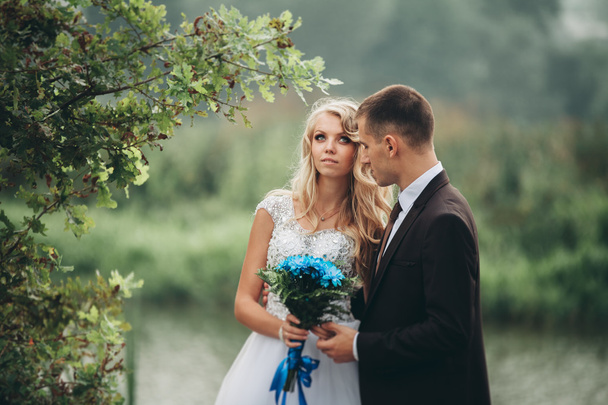 romantisches Hochzeitspaar, Mann und Frau posieren in der Nähe des schönen Sees - Foto, Bild