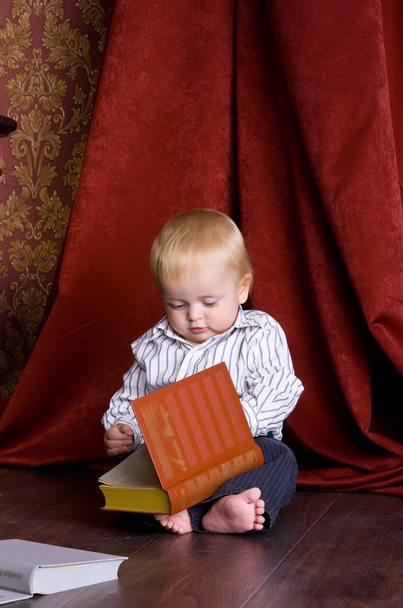 Хлопчик читає книгу, що сидить на підлозі
 - Фото, зображення