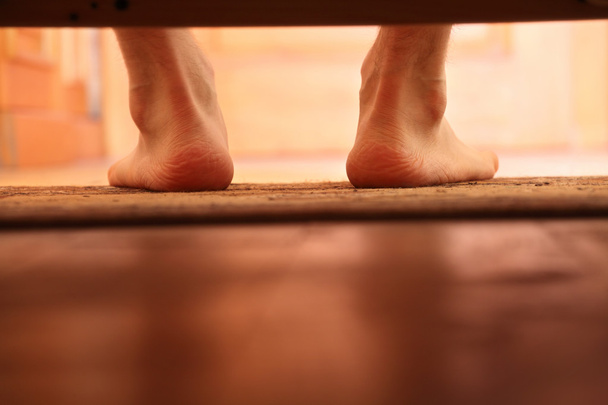 male bare feet photo from under the bed - Photo, Image