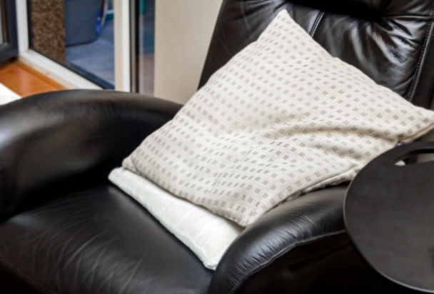 Pillows in black leather comfort chair - 写真・画像