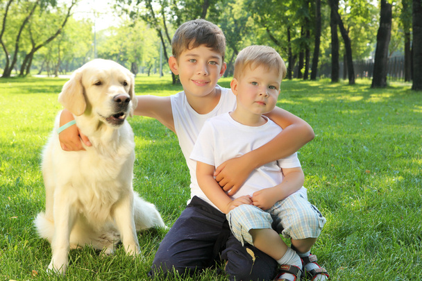 twee broers in het park met een hond - Foto, afbeelding