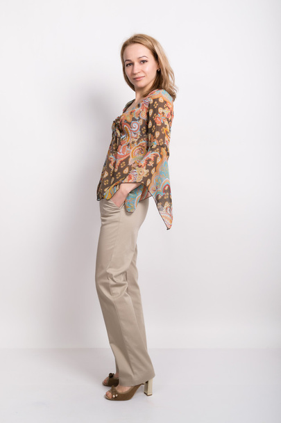 linda menina loira em um top colorido e calças cinza posando
 - Foto, Imagem