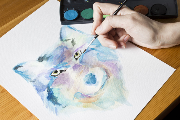 Artysta maluje obraz wilka, przy użyciu pędzla i akwarela malarstwo kolorowy - Zdjęcie, obraz