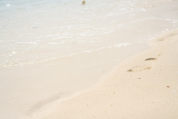 Voet afdrukken op een zand strand in zonnige dag - Foto, afbeelding