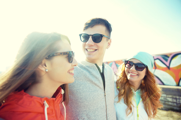 happy teenage friends in shades talking on street - Фото, зображення