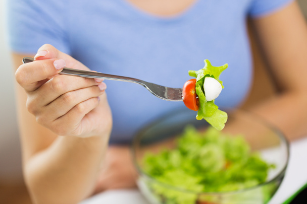 закрыть глаза на молодую женщину, которая ест салат дома
 - Фото, изображение