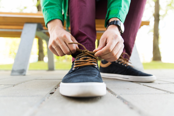 primer plano de manos masculinas atando cordones de zapatos en la calle
 - Foto, Imagen