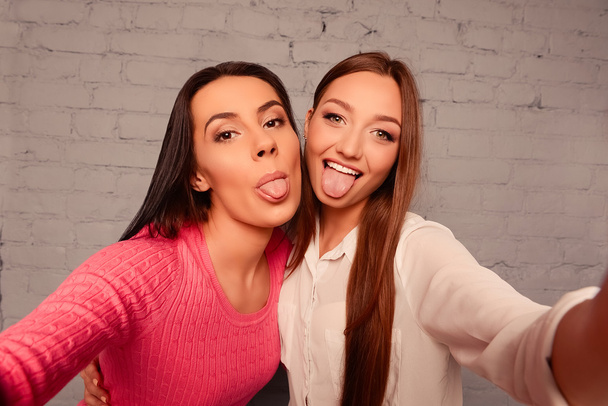 Happy funny girlfriends make selfie photos and showing tongue - Foto, Imagem