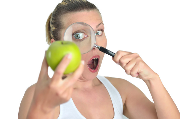 Mujer feliz rubia sana mirando manzana verde con una lupa
 - Foto, imagen
