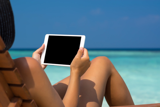 Blank empty tablet computer in the hands of women on the beach - Photo, image
