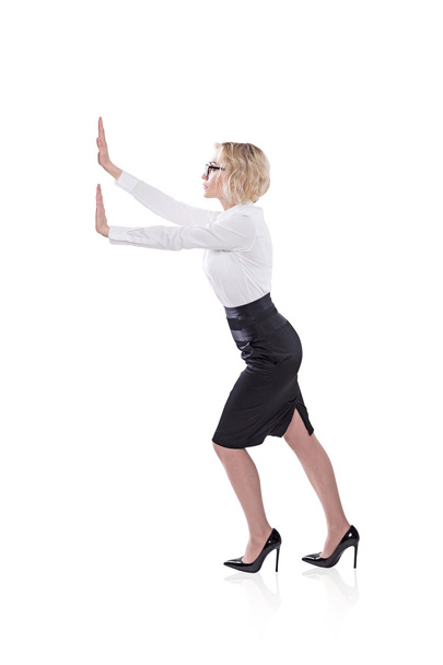 A businesswoman pushing an imaginary wall. Side view. Isolated. Concept of effort. - Foto, imagen