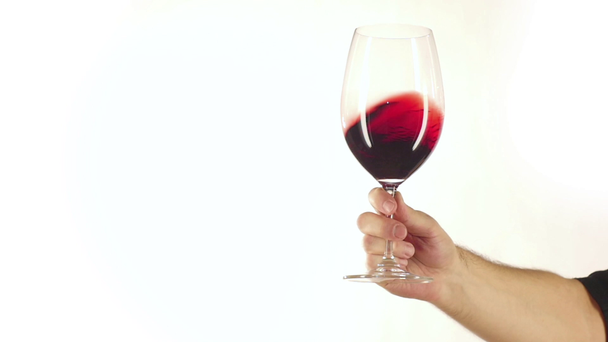 Glass of red wine with splashes in hand, white, slowmotion - Footage, Video