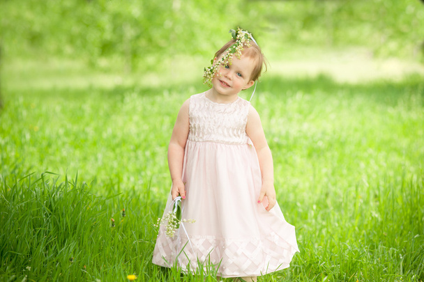 Sweet baby girl in wreath of flowers smiling outdoors - Photo, Image