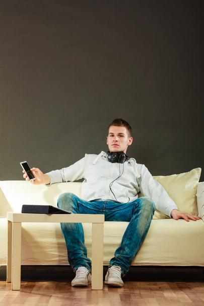 man on couch with headphones smartphone and tablet - Foto, imagen