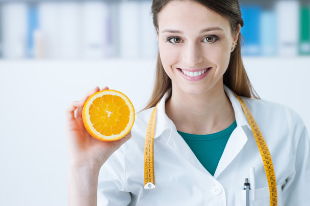Nutritionist holding a sliced orange - Фото, изображение