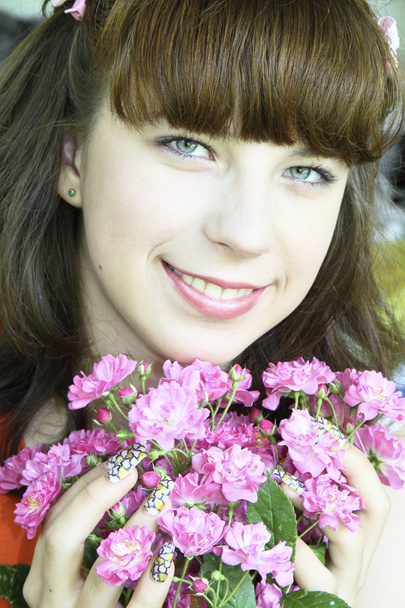 das Porträt des fröhlichen Mädchens mit rosa Blumen - Foto, Bild