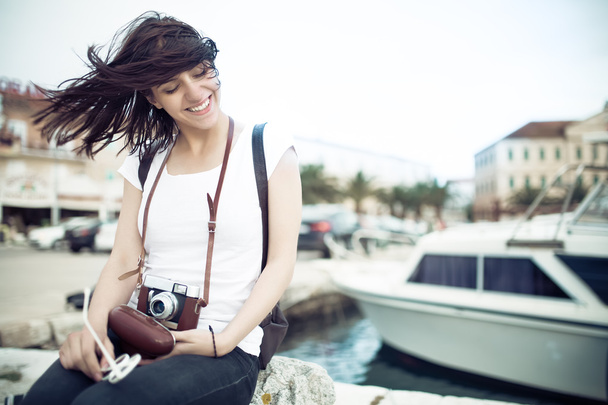 Summer hipster beach woman fun holding vintage retro camera laughing and smiling happy during summer holiday vacation travel.Women sitting on sea deck near marine boat - Photo, Image