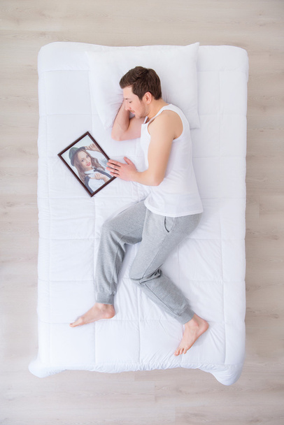 Pleasant man sleeping with portrait of his sweetheart - Φωτογραφία, εικόνα