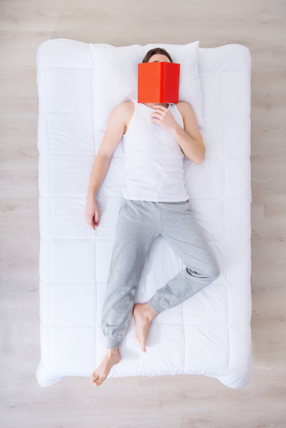 Sleeping man lying in bed with book - Fotó, kép