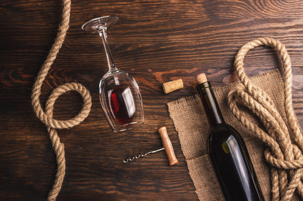 Copa con vino, botella, sacacorchos y arpillera, fondo de madera
 - Foto, imagen