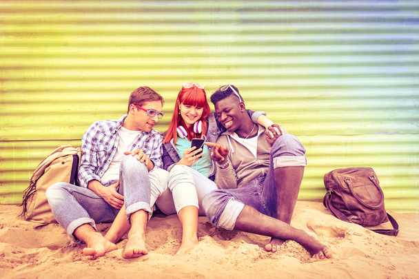 Group of happy multiracial friends having fun together using mobile smart phone - Young hipster people addicted by smartphone on social network community - Multicolored halos on vintage filtered look - Fotografie, Obrázek