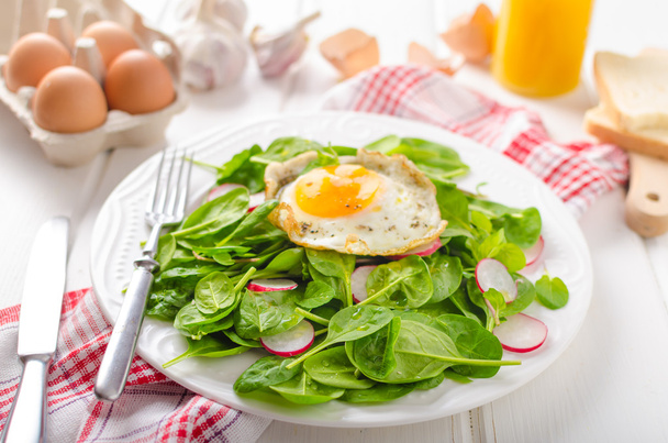 Fresh spinach, radish salad with fried egg - Foto, afbeelding