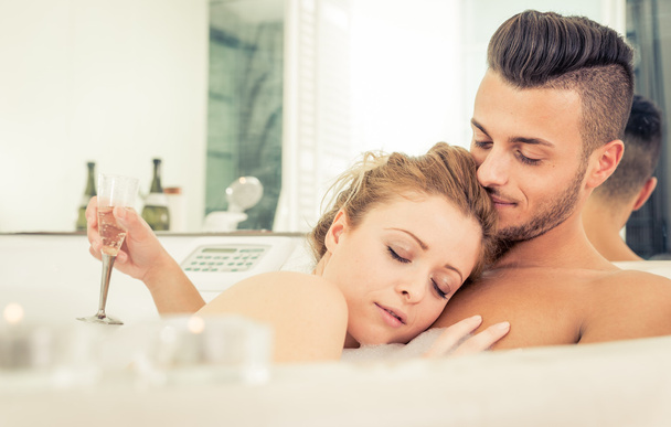 Young happy successful couple enjoying an hot bath in the jacuzi - Foto, afbeelding