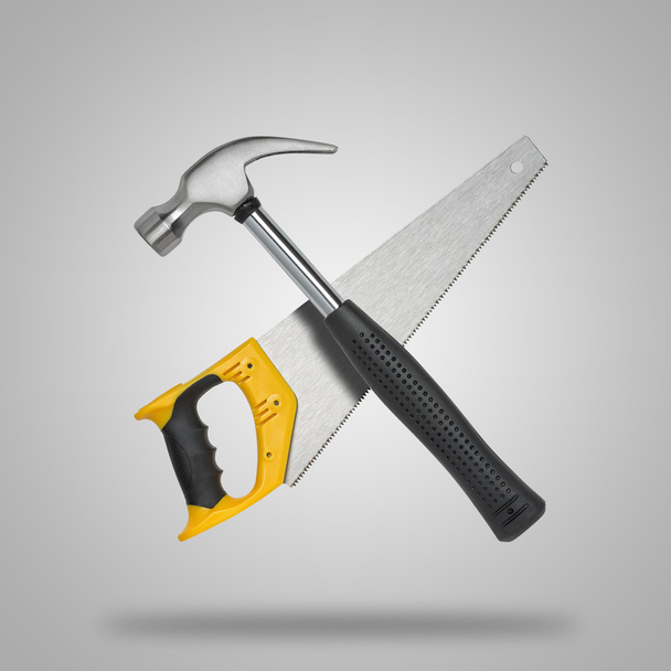 Crossed saw and hammer on gray background like icon - Photo, Image