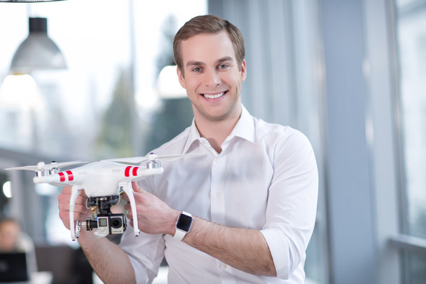 Attractive male freelancer is presenting a quadrocopter - Foto, Imagen