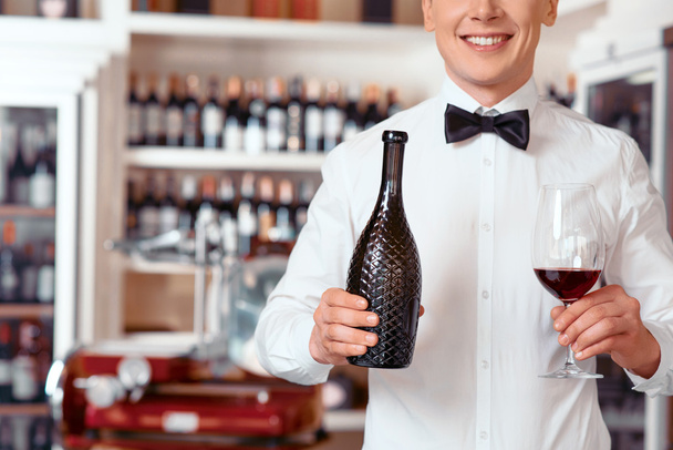 Smiling sommelier holding glass of wine - Фото, изображение