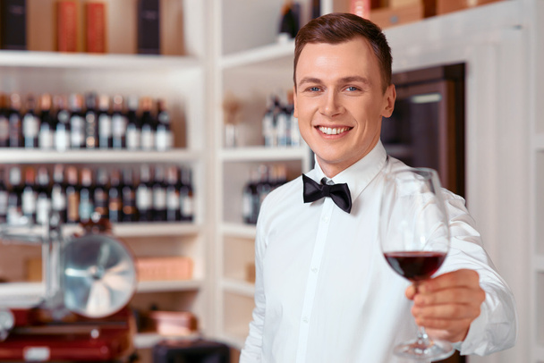 Handsome sommelier holding glass of wine - Photo, Image