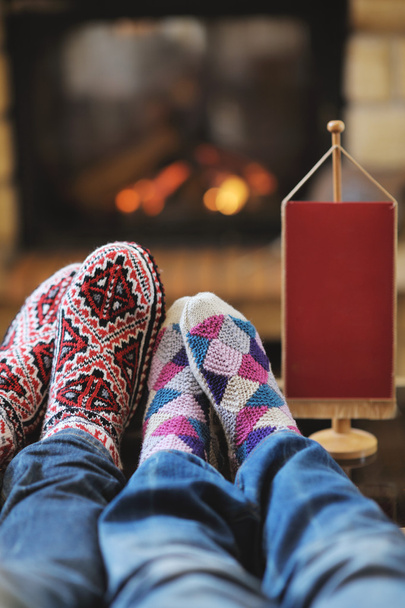 Young romantic couple sitting and relaxing in front of fireplace at home - Foto, afbeelding
