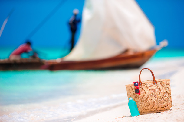 Accessori da spiaggia - borsa di paglia, bottiglia di crema solare e occhiali da sole rossi sulla spiaggia
 - Foto, immagini