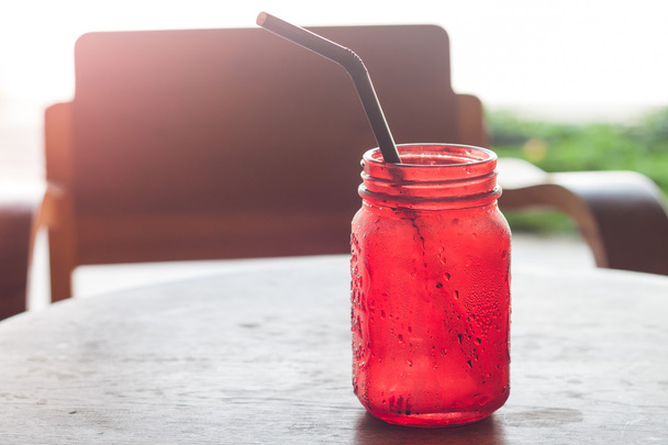 Bebida helada en vidrio rojo sobre mesa de madera
 - Foto, imagen