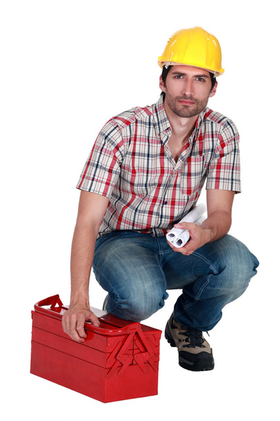 Builder carrying plans and a toolbox - Photo, Image