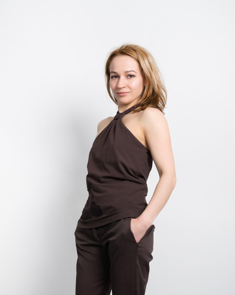 Beautiful young leggy blonde in a  brown top with bare shoulders and pants posing - Valokuva, kuva