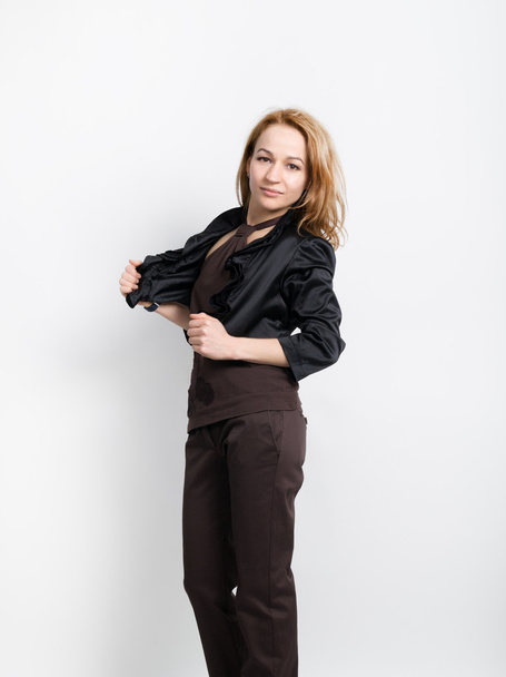 Beautiful young leggy blonde in a  brown top, black jacket and pants posing - Fotó, kép